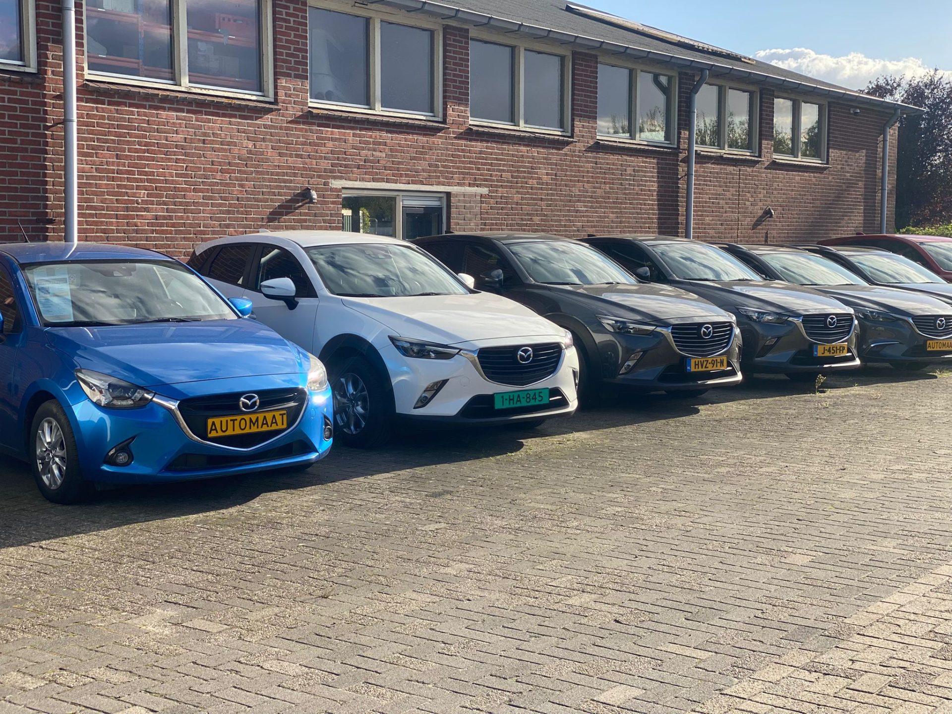 Een rij Mazda's voor het bakstenen pand van Auto Leeftink in Aadorp